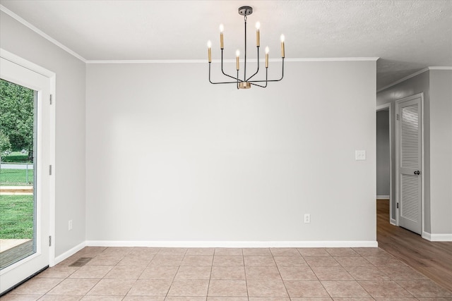 unfurnished dining area with light tile patterned floors, a chandelier, a textured ceiling, and ornamental molding