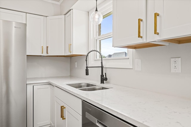 kitchen with sink, light stone countertops, appliances with stainless steel finishes, decorative light fixtures, and white cabinetry