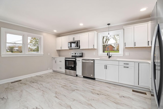 kitchen featuring plenty of natural light, sink, decorative light fixtures, white cabinetry, and stainless steel appliances