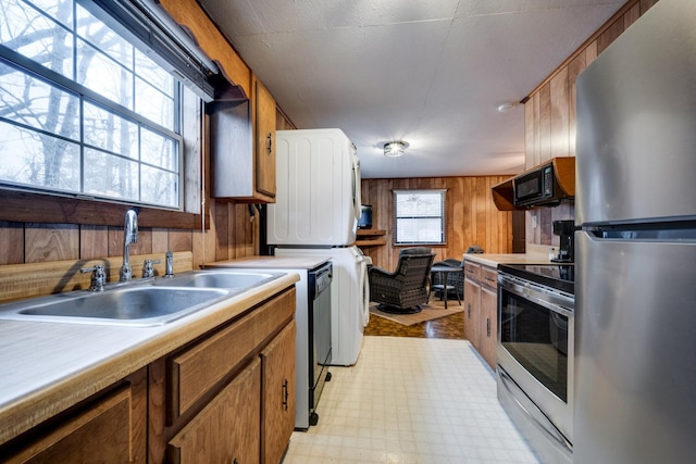 kitchen with sink, washer / clothes dryer, wooden walls, and black appliances