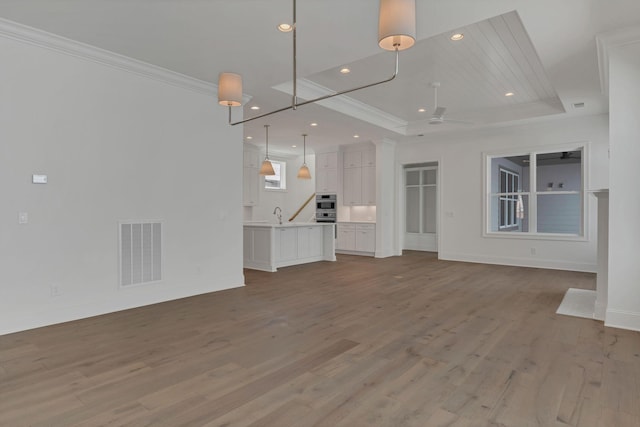 unfurnished living room with recessed lighting, visible vents, a ceiling fan, a raised ceiling, and crown molding