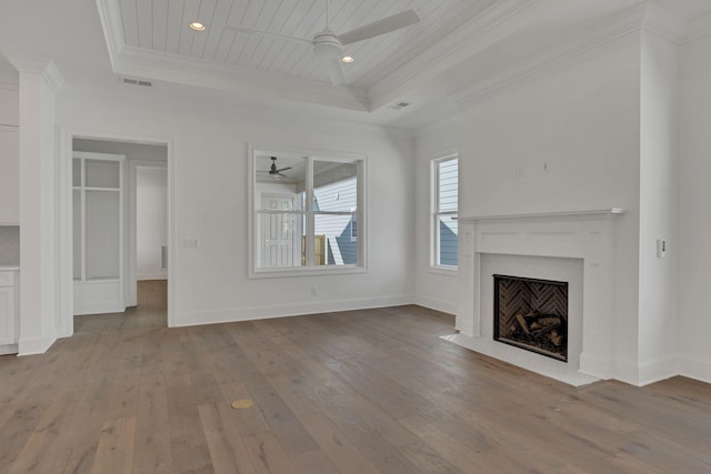 unfurnished living room with ornamental molding, a tray ceiling, visible vents, and light wood finished floors