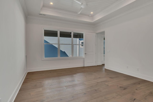 spare room featuring a ceiling fan, a tray ceiling, wood finished floors, and ornamental molding