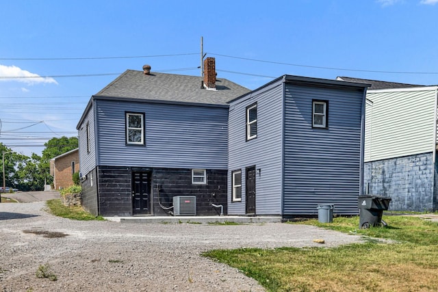 back of property featuring central AC unit and a yard