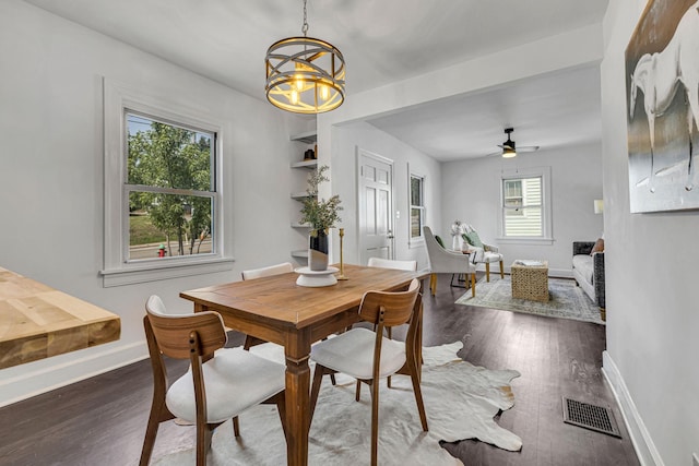 dining room featuring ceiling fan with notable chandelier, plenty of natural light, and dark wood-type flooring