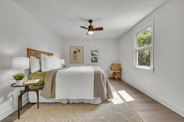 bedroom with hardwood / wood-style flooring, ceiling fan, and a textured ceiling