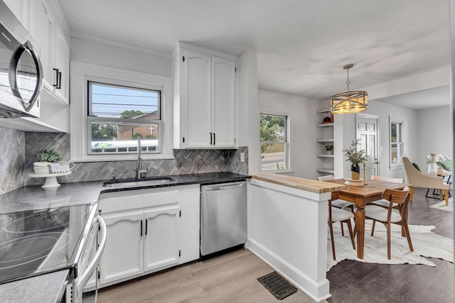 kitchen featuring sink, white cabinets, pendant lighting, and appliances with stainless steel finishes