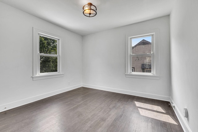 empty room with a wealth of natural light and dark hardwood / wood-style flooring