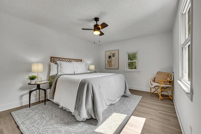 bedroom with a textured ceiling, light hardwood / wood-style floors, and ceiling fan