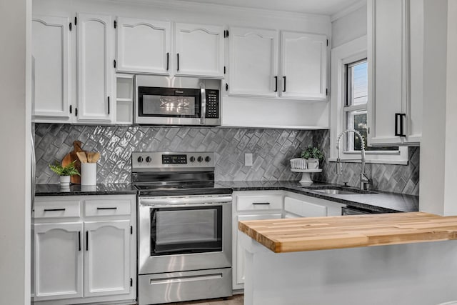 kitchen featuring white cabinetry, sink, stainless steel appliances, dark stone countertops, and decorative backsplash