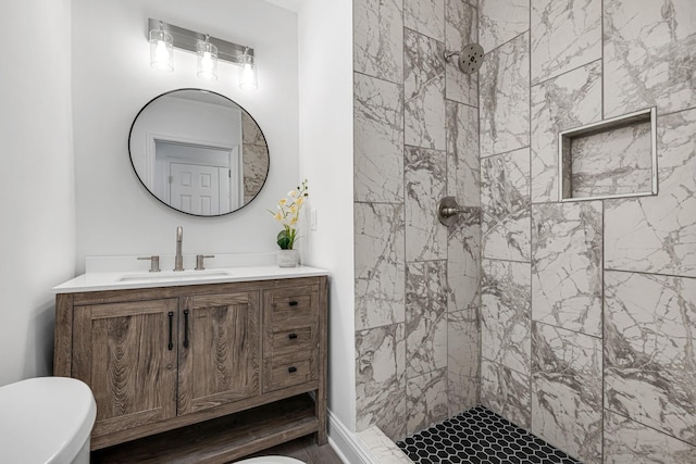 bathroom featuring vanity, toilet, and tiled shower