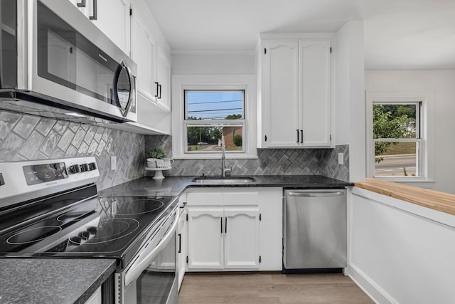 kitchen with tasteful backsplash, stainless steel appliances, sink, white cabinets, and light hardwood / wood-style floors