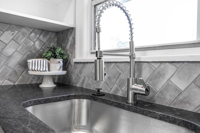 details with backsplash, dark stone counters, and sink