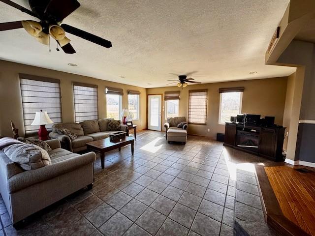 living room featuring a textured ceiling, dark tile patterned floors, and ceiling fan