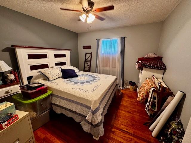 bedroom featuring ceiling fan, a textured ceiling, and dark wood-type flooring