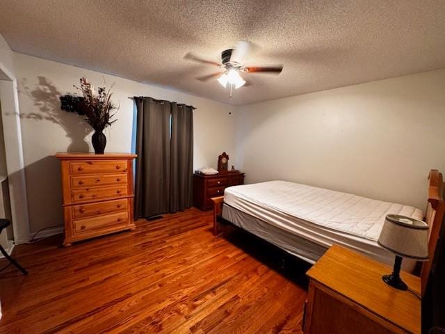 bedroom with ceiling fan, dark hardwood / wood-style floors, and a textured ceiling