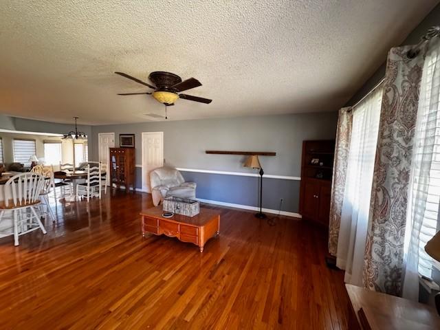 unfurnished room featuring a textured ceiling, dark wood-type flooring, and ceiling fan with notable chandelier