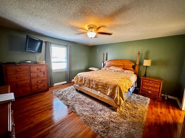 bedroom with a textured ceiling, dark hardwood / wood-style flooring, and ceiling fan