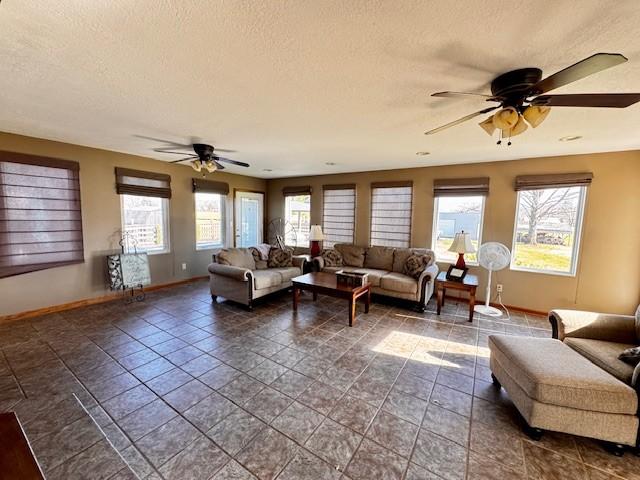 living room with ceiling fan, dark tile patterned flooring, and a textured ceiling