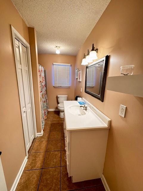 bathroom with tile patterned floors, vanity, toilet, and a textured ceiling