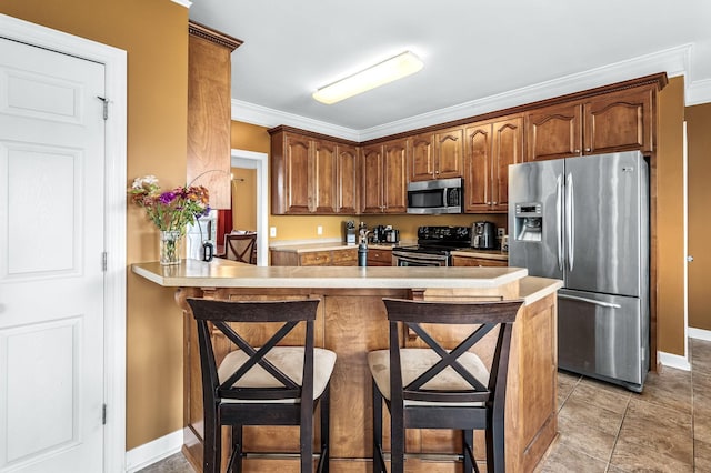 kitchen with crown molding, kitchen peninsula, a breakfast bar area, and appliances with stainless steel finishes