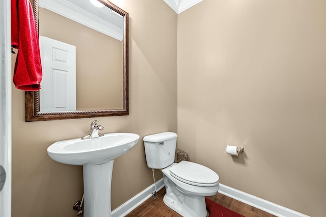 bathroom with hardwood / wood-style flooring, toilet, crown molding, and sink