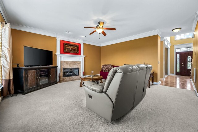 living room featuring a tile fireplace, light carpet, crown molding, and ceiling fan