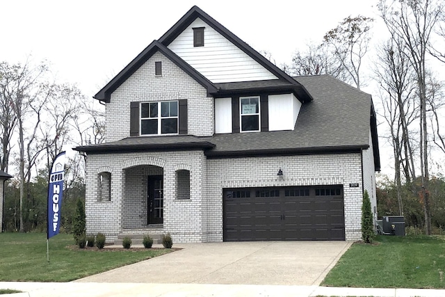 view of front of home with central air condition unit, a front lawn, and a garage