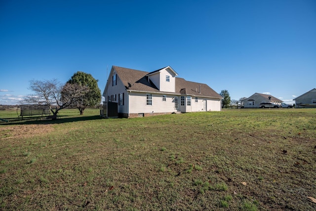 back of property featuring a yard and a trampoline