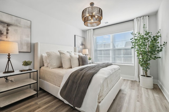 bedroom featuring hardwood / wood-style floors and an inviting chandelier