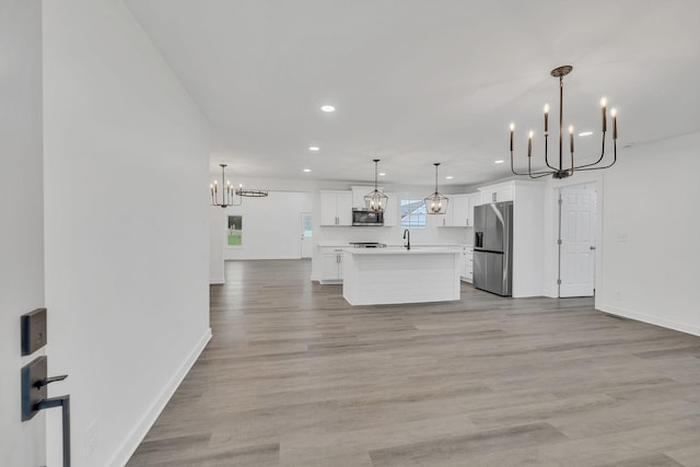 kitchen featuring white cabinets, decorative light fixtures, a center island, and stainless steel appliances