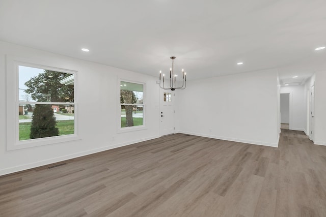 unfurnished dining area with a chandelier and light hardwood / wood-style flooring