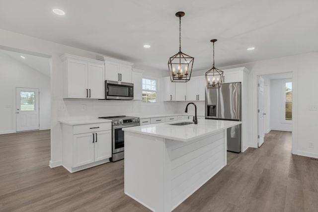 kitchen featuring sink, white cabinets, stainless steel appliances, and a center island with sink