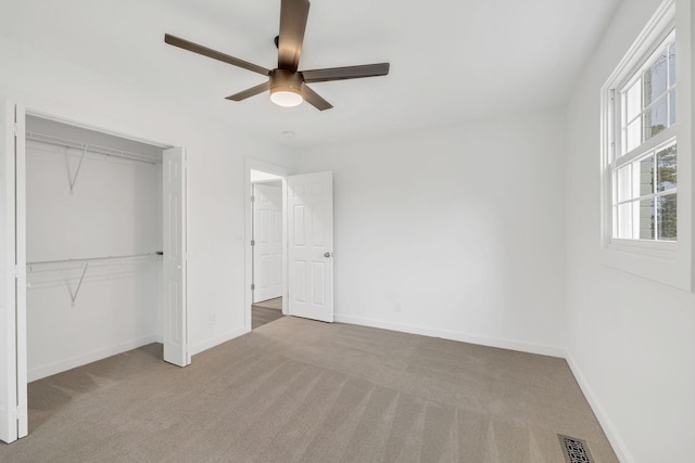 unfurnished bedroom with a closet, light colored carpet, and ceiling fan