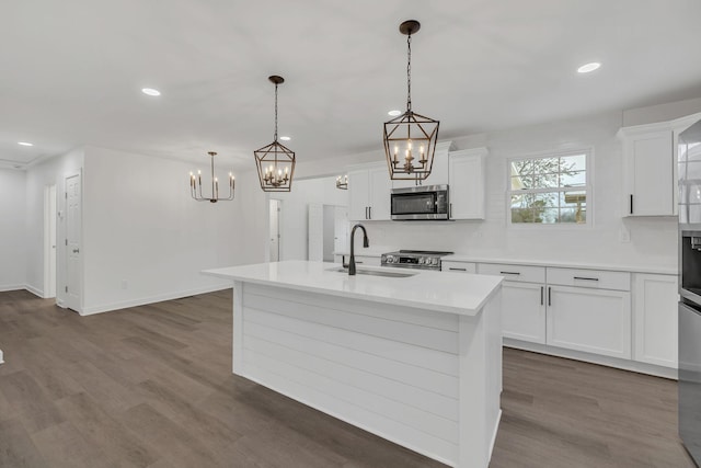 kitchen with decorative backsplash, stainless steel appliances, a kitchen island with sink, sink, and hanging light fixtures