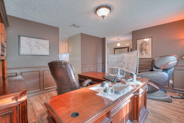 office space with a textured ceiling and light hardwood / wood-style flooring