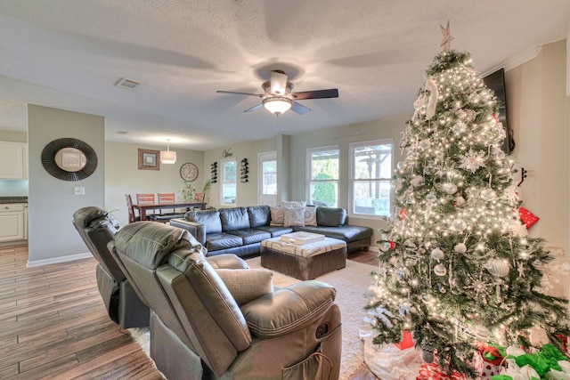 living room with ceiling fan, hardwood / wood-style floors, and a textured ceiling