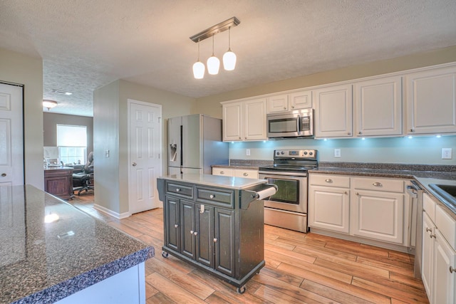 kitchen featuring white cabinetry, a center island, stainless steel appliances, pendant lighting, and a textured ceiling