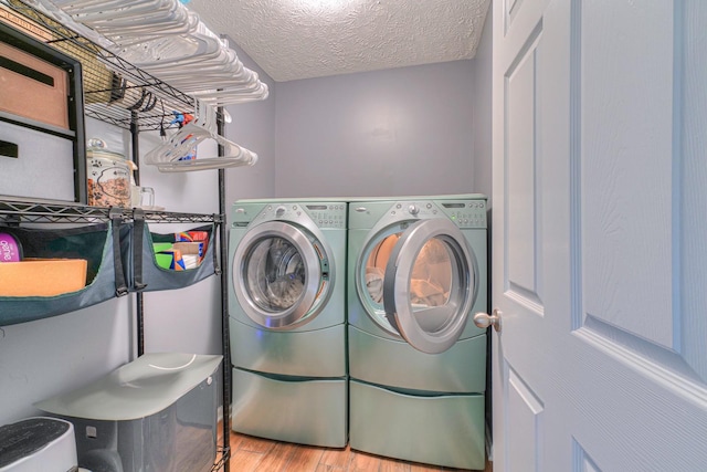 laundry area with washer and clothes dryer, light hardwood / wood-style floors, and a textured ceiling