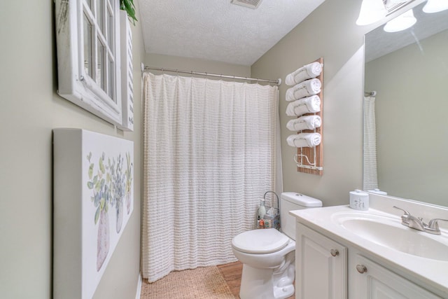 bathroom with vanity, a textured ceiling, and toilet