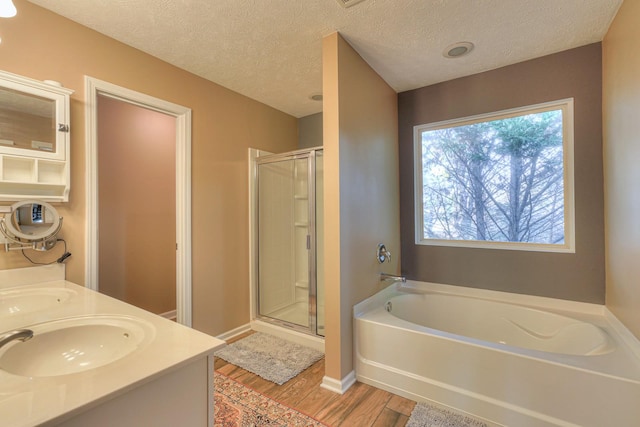 bathroom with hardwood / wood-style floors, vanity, a textured ceiling, and independent shower and bath