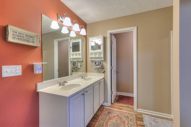 bathroom with hardwood / wood-style floors, vanity, and a textured ceiling