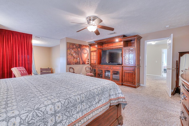 bedroom with a textured ceiling, ceiling fan, and light carpet