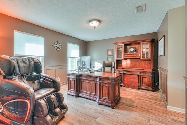 home office featuring a textured ceiling and light hardwood / wood-style floors