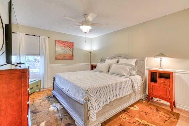 bedroom with ceiling fan, a textured ceiling, and light wood-type flooring