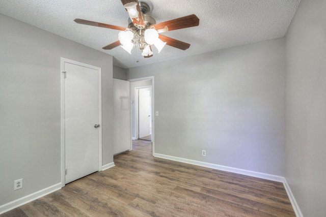 spare room featuring a textured ceiling, baseboards, and wood finished floors