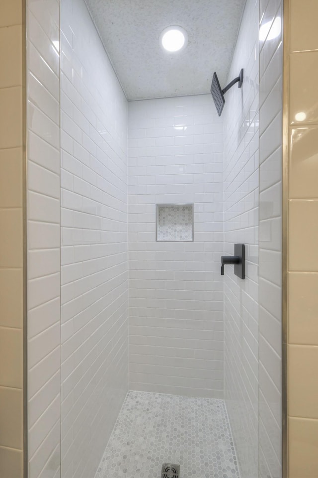 bathroom featuring a tile shower and a textured ceiling