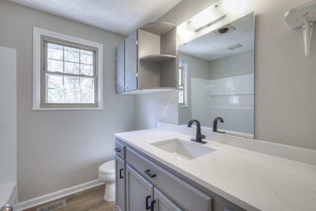 bathroom with a textured ceiling, toilet, visible vents, baseboards, and a shower