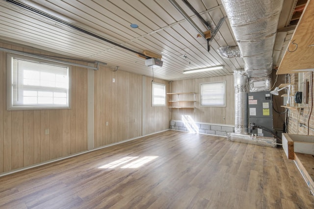 spare room with heating unit, wood walls, and wood-type flooring