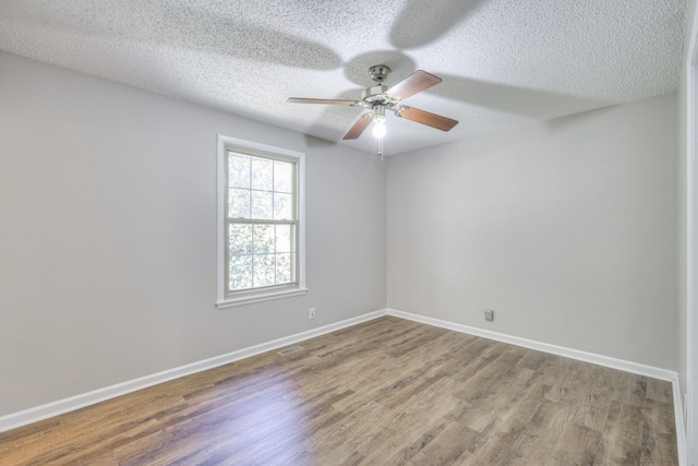 empty room featuring a ceiling fan, a textured ceiling, baseboards, and wood finished floors